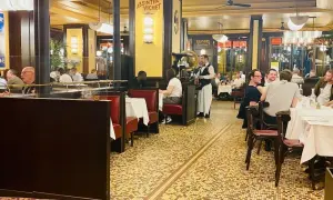 Ambiance chaleureuse dans un bouillon République, avec ses banquettes rouges, ses tables dressées et ses clients attablés.