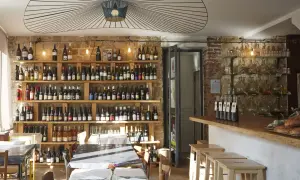Ambiance chaleureuse dans la cave à manger, avec des étagères remplies de bouteilles de vin, des tables dressées et un bar en bois.