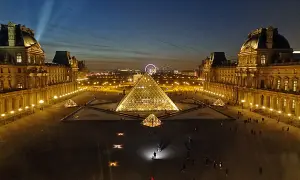 La Pyramide du Louvre illuminée, une belle soirée du 14 juillet. La foule admire le spectacle nocturne.