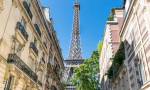 La Tour Eiffel se dresse entre des immeubles parisiens. Un aperçu parfait pour un paris visite pass.