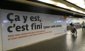 Panneau RATP annonçant la fin des travaux sur le RER A. Une personne en fauteuil roulant passe devant.