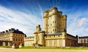 Le majestueux **Château de Vincennes** se dresse sous un ciel bleu éclatant, ses tours imposantes rappelant des siècles d'histoire.