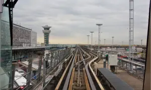 Vue depuis le train automatique Orlyval, avec la tour de contrôle et les voies ferrées. On imagine un voyage vers la Tour Eiffel.