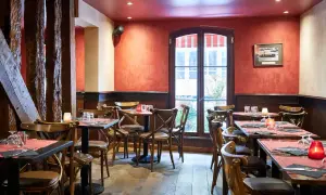 Ambiance chaleureuse au restaurant Le Molière, avec ses tables dressées, ses bougies et ses poutres apparentes.