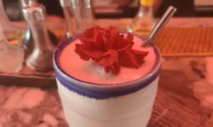 Un cocktail crémeux orné d'une fleur rouge, prêt à être dégusté. Un vrai "menu de bar-bisou" pour une soirée douce.