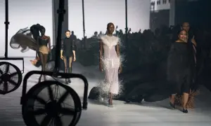 Mannequins défilent sur un podium, une robe ornée de plumes, un aperçu de la Paris Fashion Week 2026.