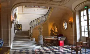 Escalier majestueux du musée Nissim de Camondo, avec sa rampe dorée, sa statue et son sol à damier.