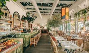Ambiance chic au Perchoir Porte de Versailles : bar animé, tables dressées, oliviers et végétation luxuriante pour un repas en terrasse.