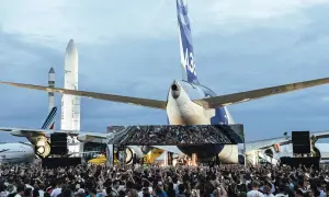 Foule immense devant une scène, sous des avions et des fusées. Ambiance de festival Cercle.