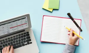 Planification des jours fériés 2026 sur un calendrier d'ordinateur. Une main écrit dans un carnet à côté.