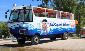 Un bus amphibie décoré de "Les Canards de Paris" avec un canard cartoon, prêt pour une aventure sur l'eau et la terre.