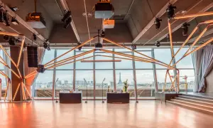 Salle de réception moderne avec vue panoramique sur Paris, éclairage néon, bar et scène. La Tour Eiffel est visible au loin.