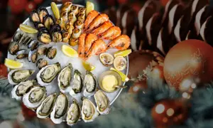 Plateau de fruits de mer frais, une tradition de Noël en France, avec huîtres, crevettes, moules et bigorneaux, sur un lit de glace, décoré de citrons et d'une sauce.