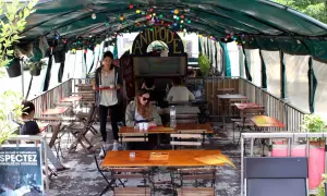 Terrasse animée d'un café-restaurant sur une péniche à Paris, avec des tables en bois, des lumières colorées et des plantes.