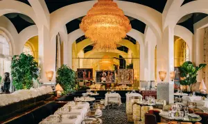Un restaurant romantique à Paris, avec un lustre orange spectaculaire, des banquettes sombres, des tables dressées et des œuvres d'art.