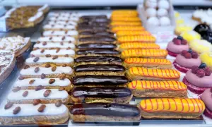 Une alléchante liste pâtisserie française : éclairs au chocolat, à la vanille et au glaçage jaune rayé de rouge, ainsi que des tartelettes aux amandes.
