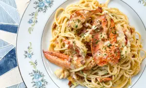 Délicieux spaghetti aux morceaux de homard, nappés d'une sauce crémeuse et parsemés de ciboulette. Un plat de pâtes au homard qui fait rêver.
