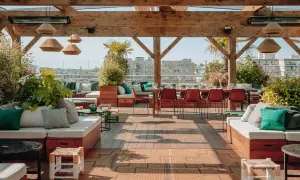Le perchoir Ménilmontant, un rooftop chic avec vue sur Paris. Canapés confortables, tables dressées, végétation luxuriante et ambiance estivale.