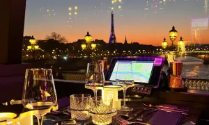 Vue sur Paris au crépuscule, avec la Tour Eiffel illuminée. Une table dressée pour un dîner romantique, parfaite pour savoir où manger après minuit.