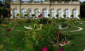 Jardin fleuri devant un bâtiment classique, avec des arches et des fenêtres, au Bois de Boulogne.