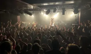 Foule en délire dans une salle de concert, le nombre de places semble limité mais l'ambiance est électrique.
