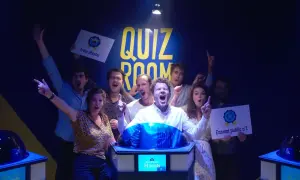 Équipe joyeuse dans une "Quiz Room" à Paris La Villette, célébrant une victoire. Ils tiennent des pancartes "Joker Master" et "Ennemi public n°1".