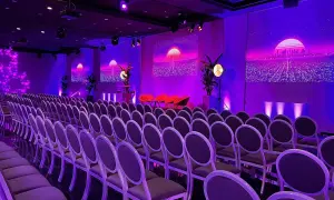 Un auditorium à Paris, baigné de lumières violettes, prêt pour un événement futuriste. Des rangées de chaises attendent les invités.