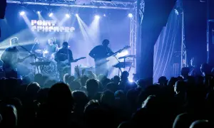 Un groupe joue sur scène sous des lumières bleues. Découvrez les **upcoming concerts in Paris** !