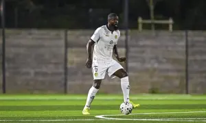 Joueur de football en action sur la pelouse du stade Charléty, concentré sur le ballon.