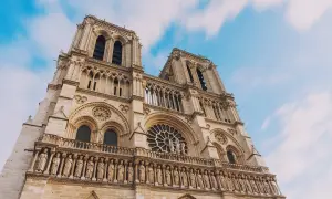 Notre Dame de Paris, une visite inoubliable. La façade majestueuse de la cathédrale se dresse sous un ciel bleu et nuageux.
