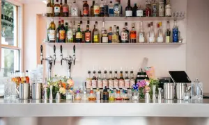 Bar à cocktails prêt à servir, avec des bouteilles d'alcool sur les étagères et des sirops colorés sur le comptoir. Les "bisous bisous club reviews" sont excellentes pour ce bar !
