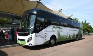 L'Aérobus Paris-Beauvais, un bus blanc et vert orné de monuments parisiens, attend des passagers sous une structure de toit.