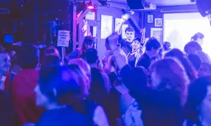 Ambiance festive dans un bar du Marais, une foule profite de la musique sous des lumières bleues et violettes.