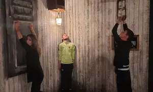 Trois personnes dans une pièce aux murs décrépits, défiant la gravité. Une femme s'accroche à un mur, un homme flotte, un autre escalade une chaise. Ambiance de **the dark dreams Paris**.