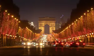 Les Champs-Élysées illuminés pour le réveillon de Noël, avec le trafic parisien et l'Arc de Triomphe en fond.