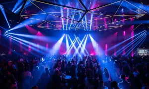 Une foule danse sous des jeux de lumière bleus et roses dans une salle de concert, évoquant l'ambiance d'un "phantom Paris" nocturne.