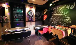 Ambiance de baby bar avec fléchettes, baby-foot et murs décorés de vinyles rock.