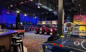Ambiance de fête foraine à Montparnasse, avec des jeux d'arcade, des tables de air hockey et des murs décorés "Smile world".