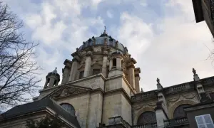 Dôme majestueux de l'église du Val-de-Grâce, se détachant sur un ciel nuageux. L'architecture baroque est impressionnante.