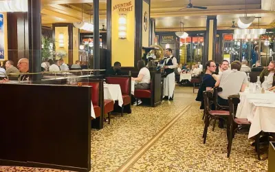 Ambiance chaleureuse dans un bouillon République, avec ses banquettes rouges, ses tables dressées et ses clients attablés.