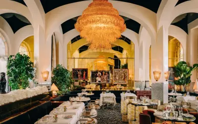 Un restaurant romantique à Paris, avec un lustre orange spectaculaire, des banquettes sombres, des tables dressées et des œuvres d'art.