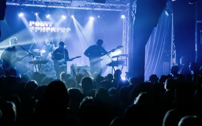 Un groupe joue sur scène sous des lumières bleues. Découvrez les **upcoming concerts in Paris** !