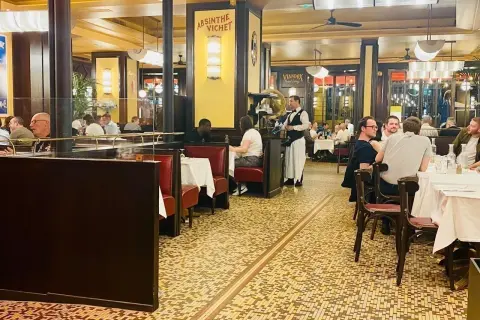 Ambiance chaleureuse dans un bouillon République, avec ses banquettes rouges, ses tables dressées et ses clients attablés.