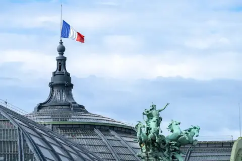 Le drapeau français flotte au sommet d'une tour du palais des congrès Paris, à côté d'une statue de quadrige.