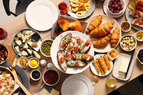 Un délicieux brunch en famille avec croissants, toasts garnis, fromages, fruits et pâtes.