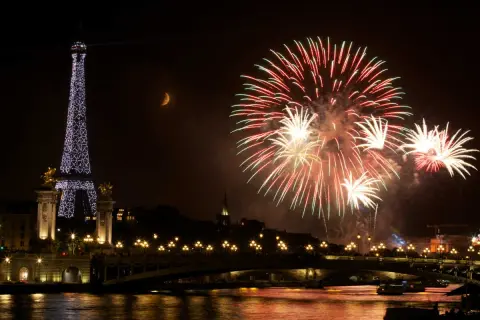 Feux d'artifice spectaculaires illuminent le ciel parisien, avec la Tour Eiffel scintillante et la lune en croissant. Une célébration mémorable pour le 3 avril férié.