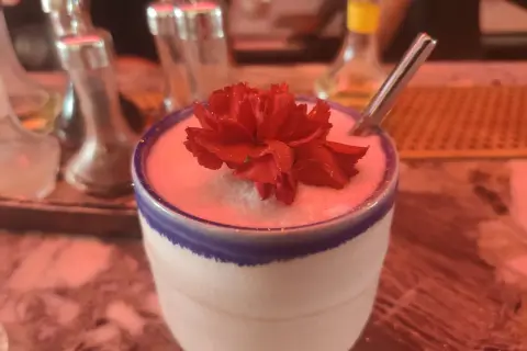 Un cocktail crémeux orné d'une fleur rouge, prêt à être dégusté. Un vrai "menu de bar-bisou" pour une soirée douce.