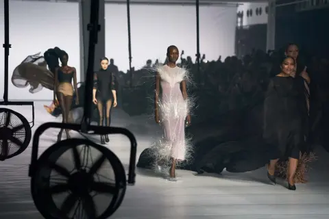 Mannequins défilent sur un podium, une robe ornée de plumes, un aperçu de la Paris Fashion Week 2026.