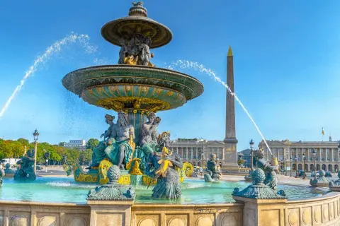 Fontaine monumentale et obélisque sur la place de la Concorde, Paris, sous un ciel bleu éclatant.
