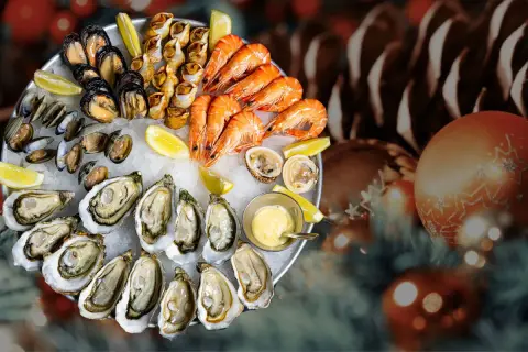 Plateau de fruits de mer frais, une tradition de Noël en France, avec huîtres, crevettes, moules et bigorneaux, sur un lit de glace, décoré de citrons et d'une sauce.
